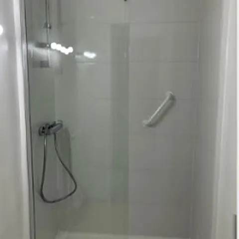 Après : douche avec paroi vitrée et faïence blanche