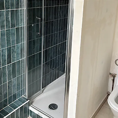 Après : douche vitrée et faïence verte, WC neuf