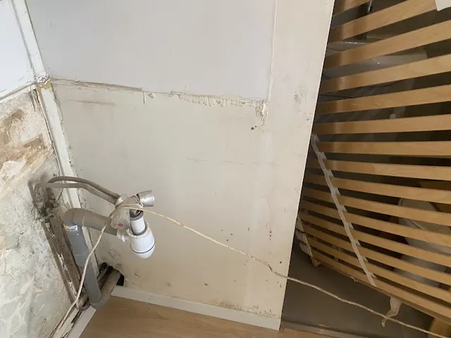 Canalisation d'évacuation apparente le long d'un mur avant intervention